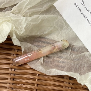 Detailed macro view of pink marble acetate barrette with golden Barrette La France lettering
