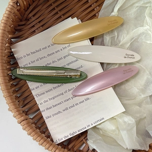Macro detail of four pearl acetate oval hair clips in mustard, beige, green and pink