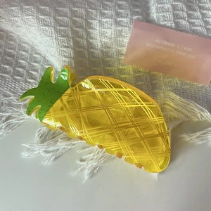 Detail of yellow pineapple hair claw clip in translucent acetate on soft textured fabric