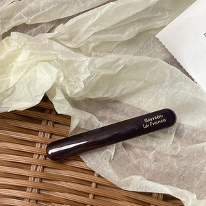 Close-up of a glossy dark brown acetate hair clip with golden Barrette La France lettering