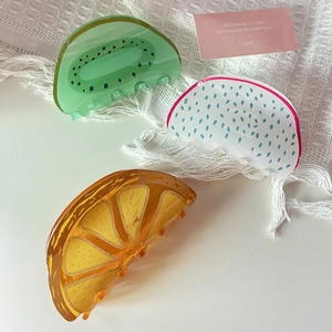 Three fruit-themed acrylic hair claws featuring kiwi, dragon fruit, and orange designs
