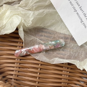 Macro shot of an acetate barrette hair clip with floral marble texture and gold lettering