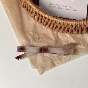 Gros plan sur une pince à cheveux effet marbre ambré et acétate sur fond vintage