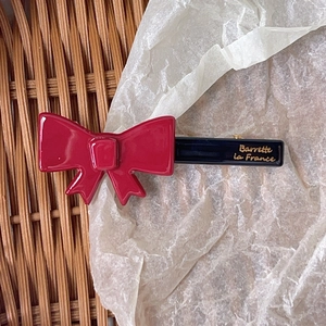Detailed macro view of red bow hair clip with gold Barrette la France script on black base