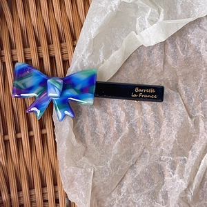 Detailed close-up of marble pattern acetate bow hair clip with gold lettering