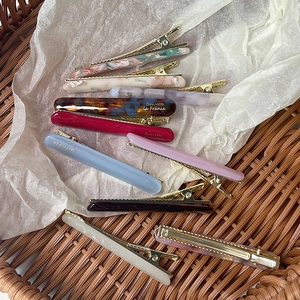 French style colorful acetate hair barrettes with gold accents on a rustic background