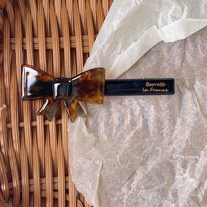 Detailed close-up of a leopard print bow hair clip with gold Barrette La France lettering