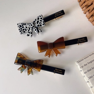Bow hair clips in leopard, amber, and spotted patterns with elegant gold branding