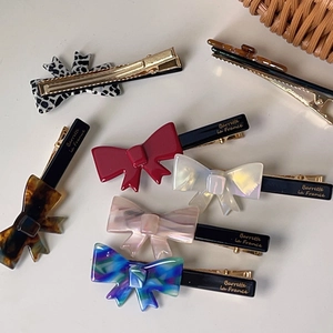 Set of six assorted French style bow hair clips with gold label on minimalist background