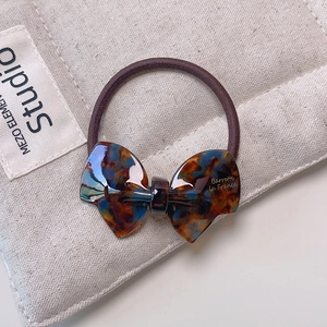 Close-up of elegant tortoise shell bow hair tie with gold Barrette la France script