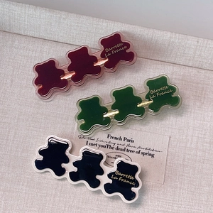 Vue détaillée de trois barrettes ours en résine rouge, verte et noire avec base dorée