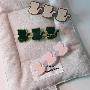 Détail de trois barrettes chat en acétate de couleurs verte, blanche et rose pâle