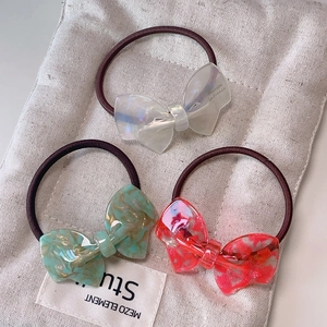 Elegant acetate bow hair ties in pearl white and marble patterns on a canvas bag