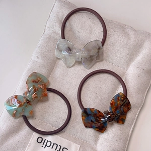 Three-piece acetate bow hair tie set in iridescent white, floral green, and tortoiseshell