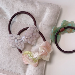 Detailed view of elegant acetate bow hair ties with marble texture and branded engraving