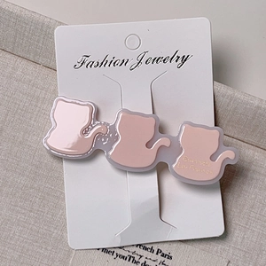 Vue macro de trois barrettes chat en acétate rose dégradé sur carte à bijoux