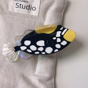 Macro shot of unique fish-shaped hair claw clip with colorful mother of pearl texture