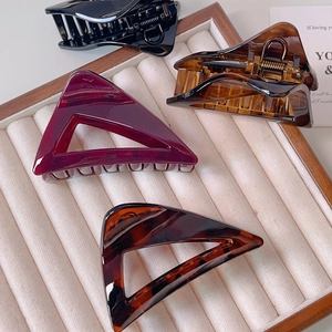 Elegant acrylic triangle claw clips in black, amber, and burgundy on a velvet tray
