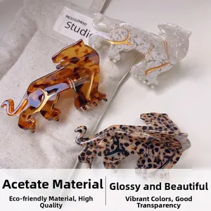 Three tiger-shaped cellulose acetate hair claws in leopard, white, and tortoiseshell patterns