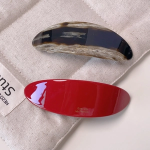 Close-up of tortoise shell and red acetate hair barrettes with golden lettering