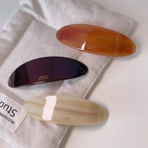 Three acetate marble-patterned barrettes on a cotton bag with a minimalist aesthetic