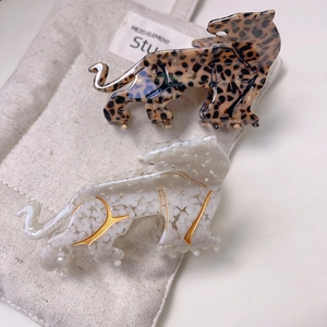 Leopard and pearl white acetate hair claw clips displayed on a beige fabric bag