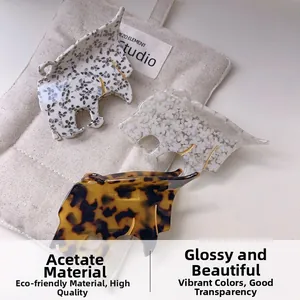 Trois pinces à cheveux en acétate avec motif guépard sur un fond en tissu doux