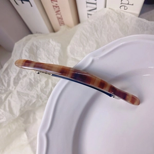 Vue détaillée d'une pince à cheveux en résine ambrée marbrée sur assiette en céramique