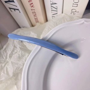 Détail d'une pince à cheveux bleu clair en acétate sur une assiette blanche
