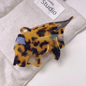 Gros plan sur la pince à cheveux teckel en acétate écaille de tortue sur lin