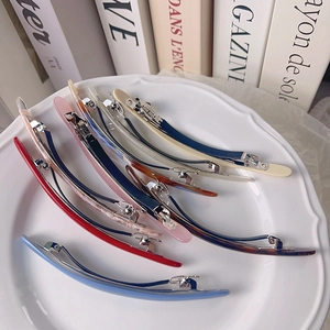 Élégantes barrettes ovales en acétate coloré présentées sur une assiette en céramique