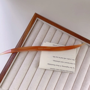 Detailed shot of amber acetate hair pin with France Handmade text on velvet tray