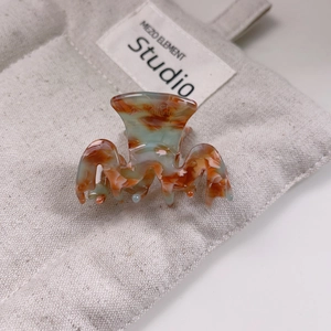 Détail d'une pince à cheveux en acétate faite main aux motifs marbrés orange et vert d'eau