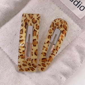 Close-up of leopard print resin hair clips on linen fabric with silver metal clips
