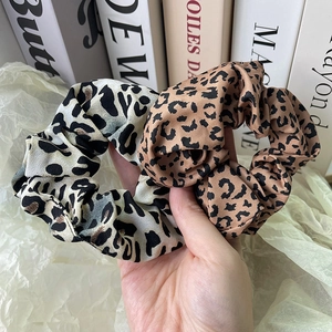 Close-up of leopard print scrunchies with silky satin texture and elastic band detail