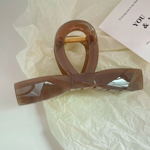 Detailed macro view of the translucent brown resin bow hair claw with gold spring