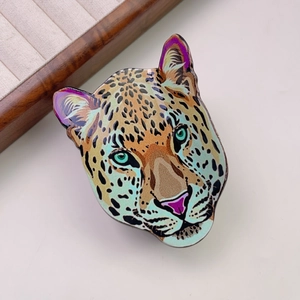 Macro shot of detailed leopard head hair claw with colorful enamel finish and green eyes