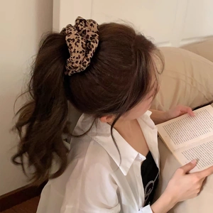Detailed view of a leopard print scrunchie used to secure a high ponytail hairstyle
