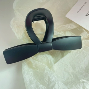 Macro shot of large matte black bow hair claw clip with focus on durable metal spring