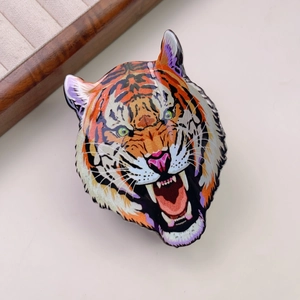 Detailed macro view of an orange leopard head hair claw with enamel finish and green eyes
