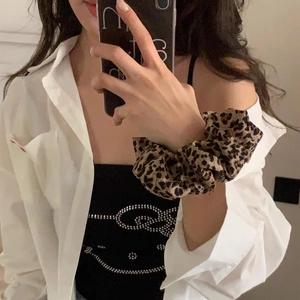 Leopard print scrunchie worn on wrist in a casual mirror selfie lifestyle shot