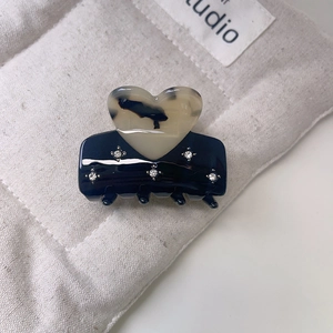 Detailed close-up of heart-shaped acetate hair claw with sparkling rhinestone accents