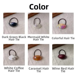 Detail showing six colors of acetate elastic hair ties on beige textured fabric