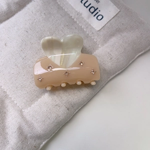 Detail of pink resin hair claw clip with heart design and champagne rhinestones