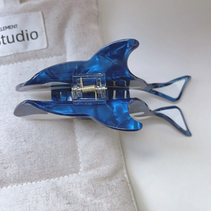 Detailed view of shark-shaped hair claw clip made of blue marbled acetate material