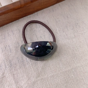 Detail of gray oval acetate resin charm on brown elastic ponytail hair tie band