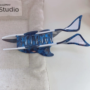 Close-up of blue marble acetate hair claw clip in a unique orca shape on soft fabric