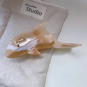 Macro detail of the glossy amber texture on this dolphin-shaped acetate hair claw clip