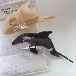 Minimalist acetate whale hair claws in orca and marble patterns on a linen bag