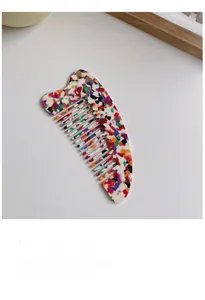 Detailed macro view of acetate hair comb with colorful terrazzo pattern on white surface